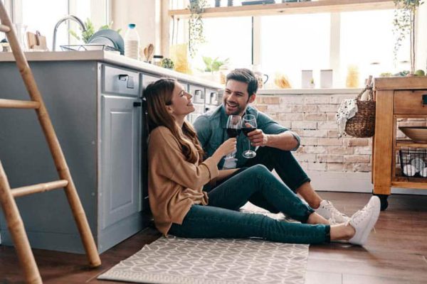 Love is in the air. Beautiful young couple drinking wine while sitting on the kitchen floor at home