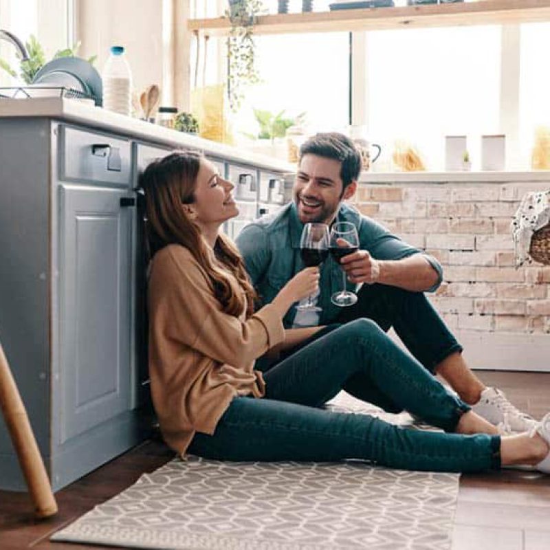 Love is in the air. Beautiful young couple drinking wine while sitting on the kitchen floor at home